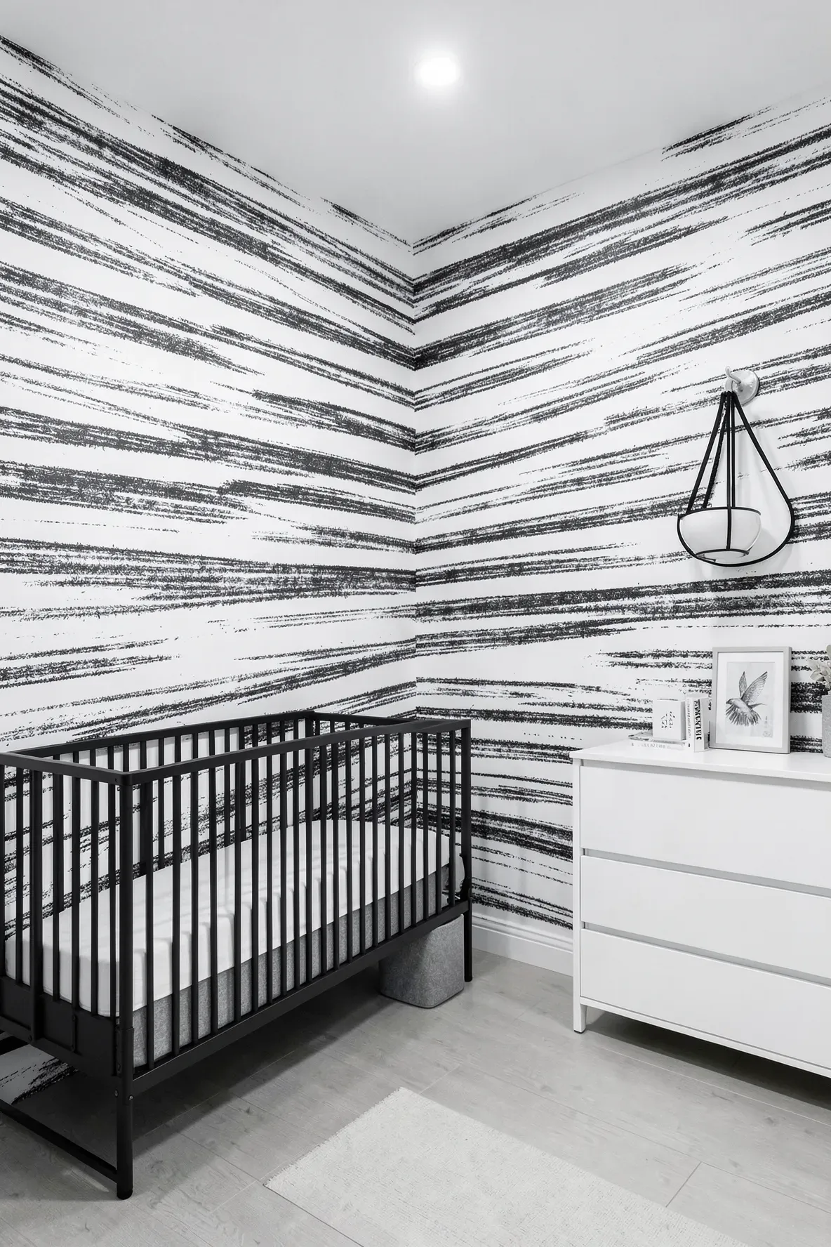 Modern nursery with hand-drawn charcoal pencil striped wallpaper and monochrome decor.