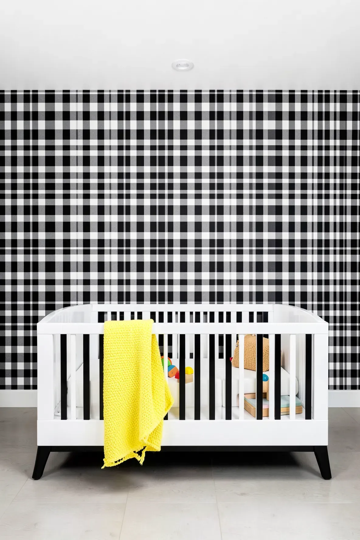 High-contrast black and white gingham wallpaper in a modern nursery with yellow accents.