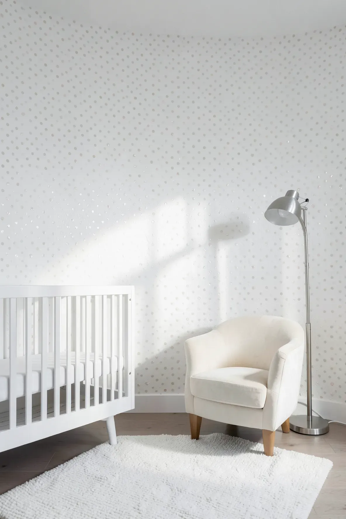 A minimalist white nursery with subtle pearlescent polka dots on the walls.
