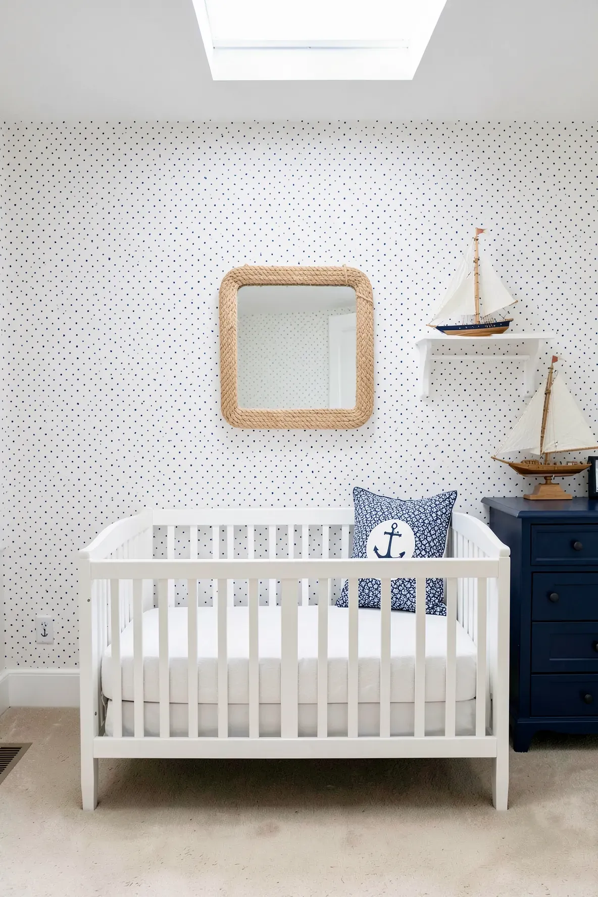 Nautical nursery with white wallpaper featuring small navy blue polka dots.