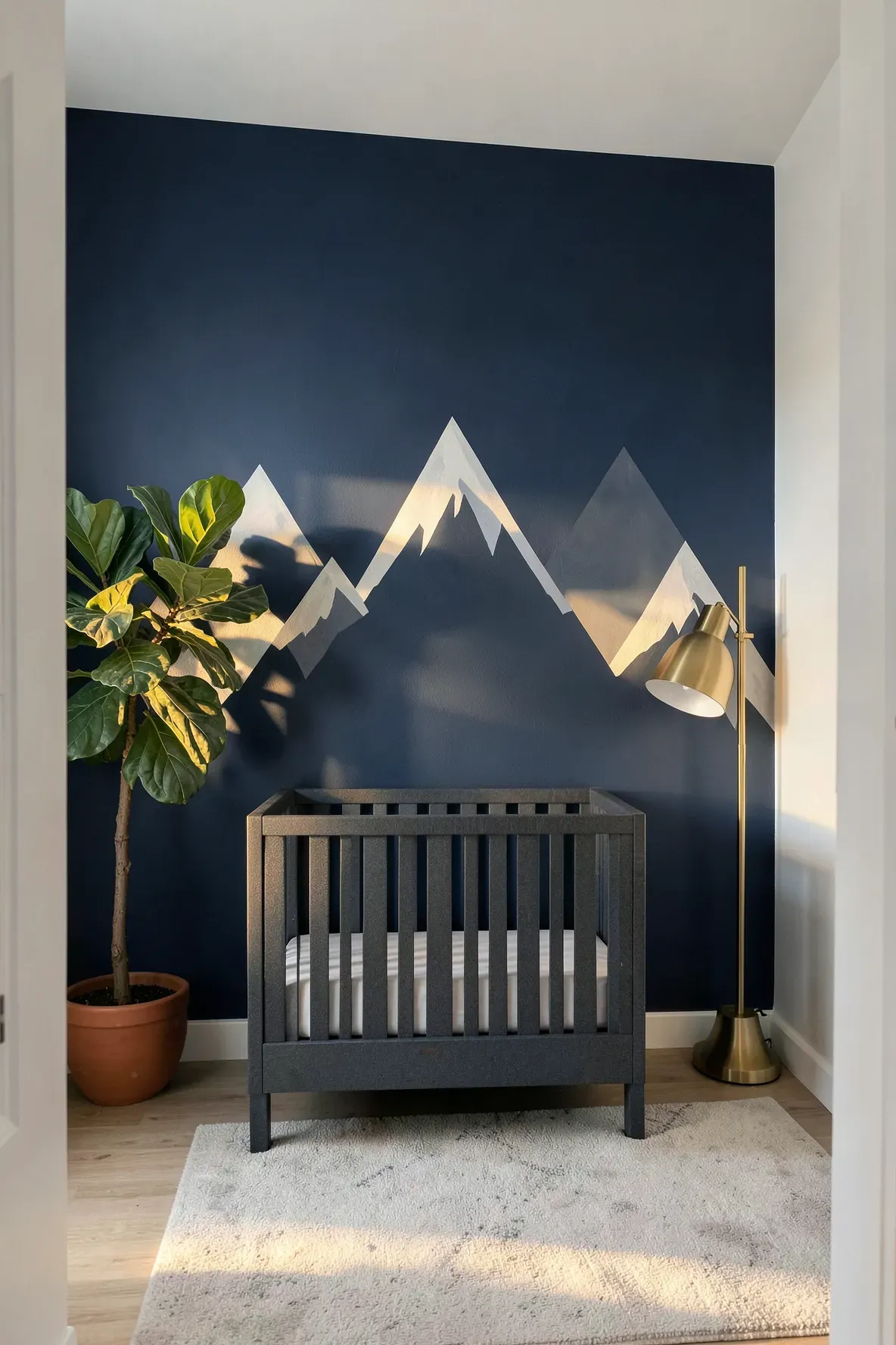 Navy blue and grey geometric mountain mural on a nursery accent wall with a grey crib.