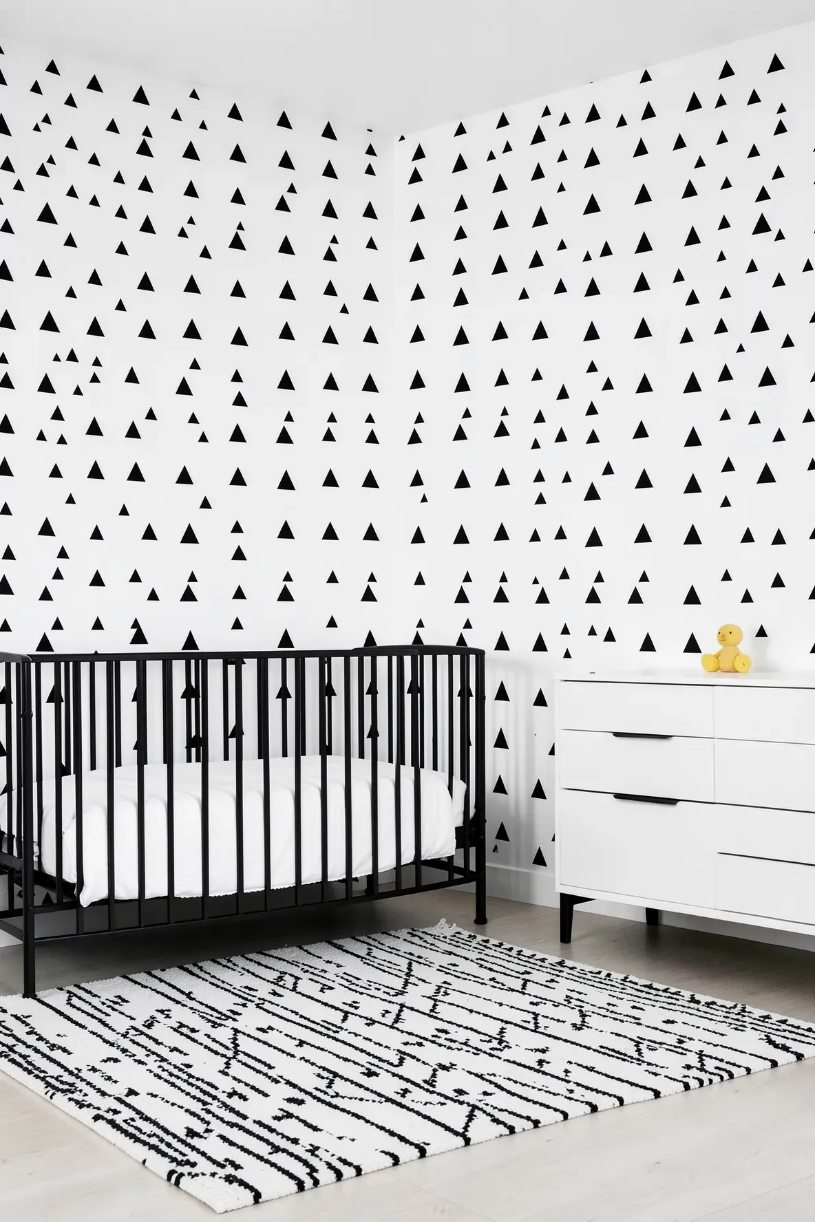 Monochrome black and white repeating triangle pattern on a modern nursery wall.