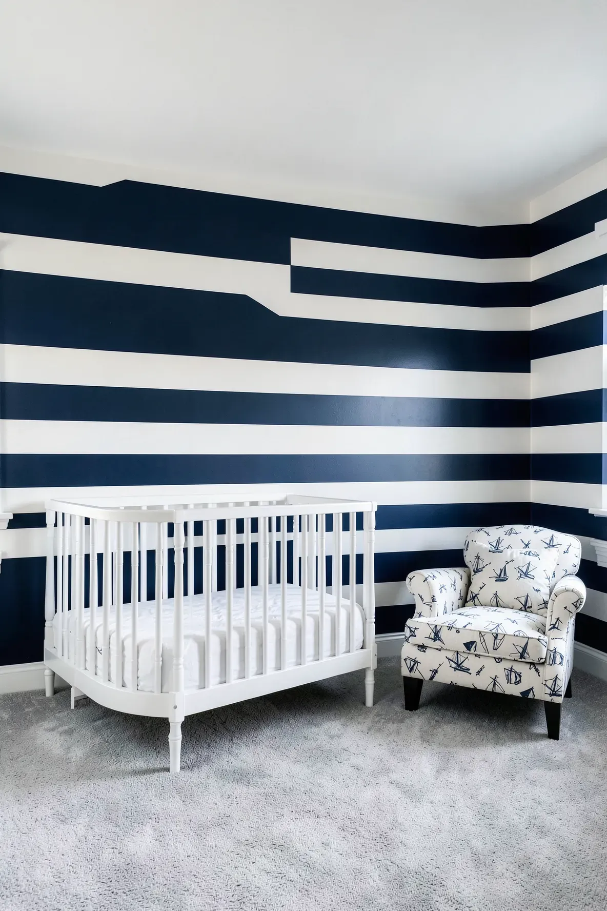 A classic nursery accent wall with wide horizontal navy blue and white stripes.