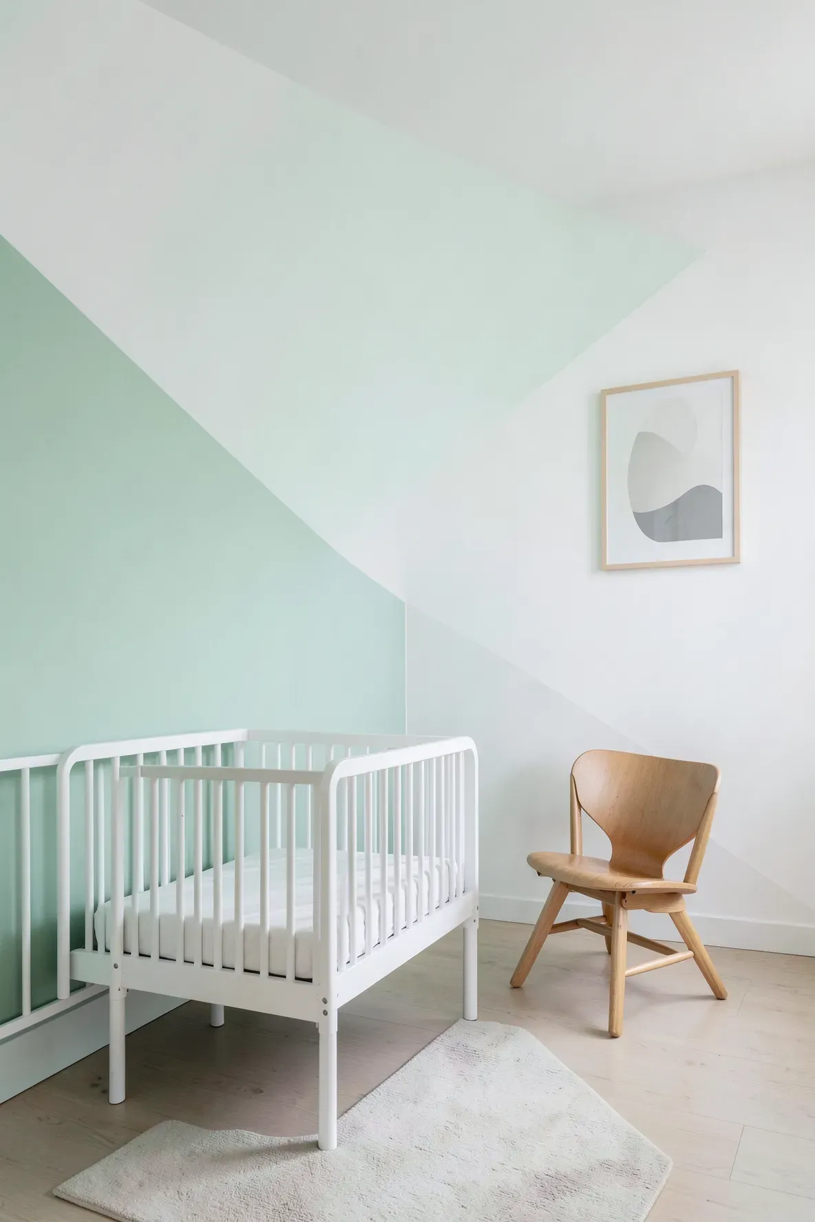A modern nursery wall with a clean diagonal split between mint green and white paint.