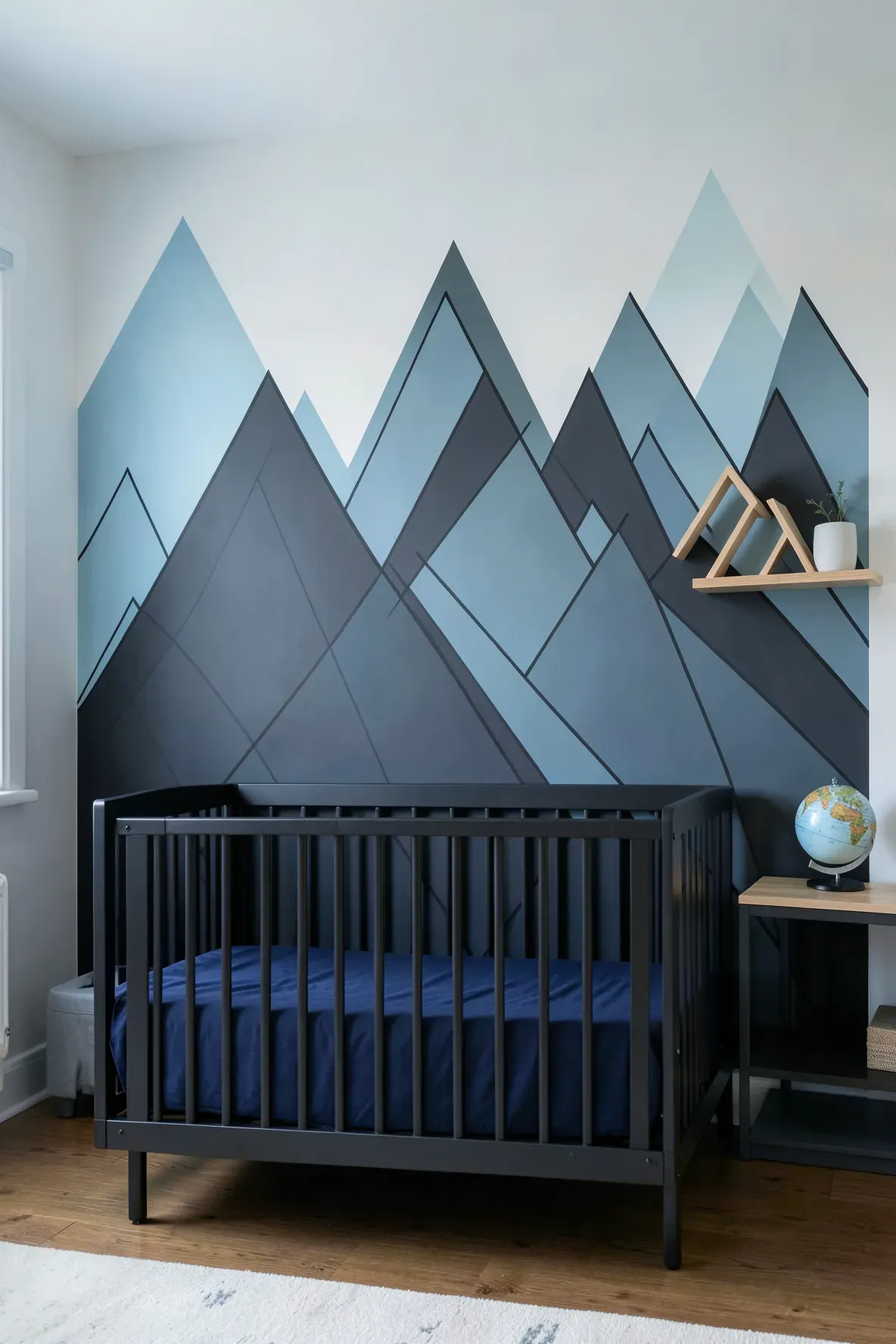 A graphic accent wall with charcoal and sky blue geometric mountain peaks in a boy's nursery.