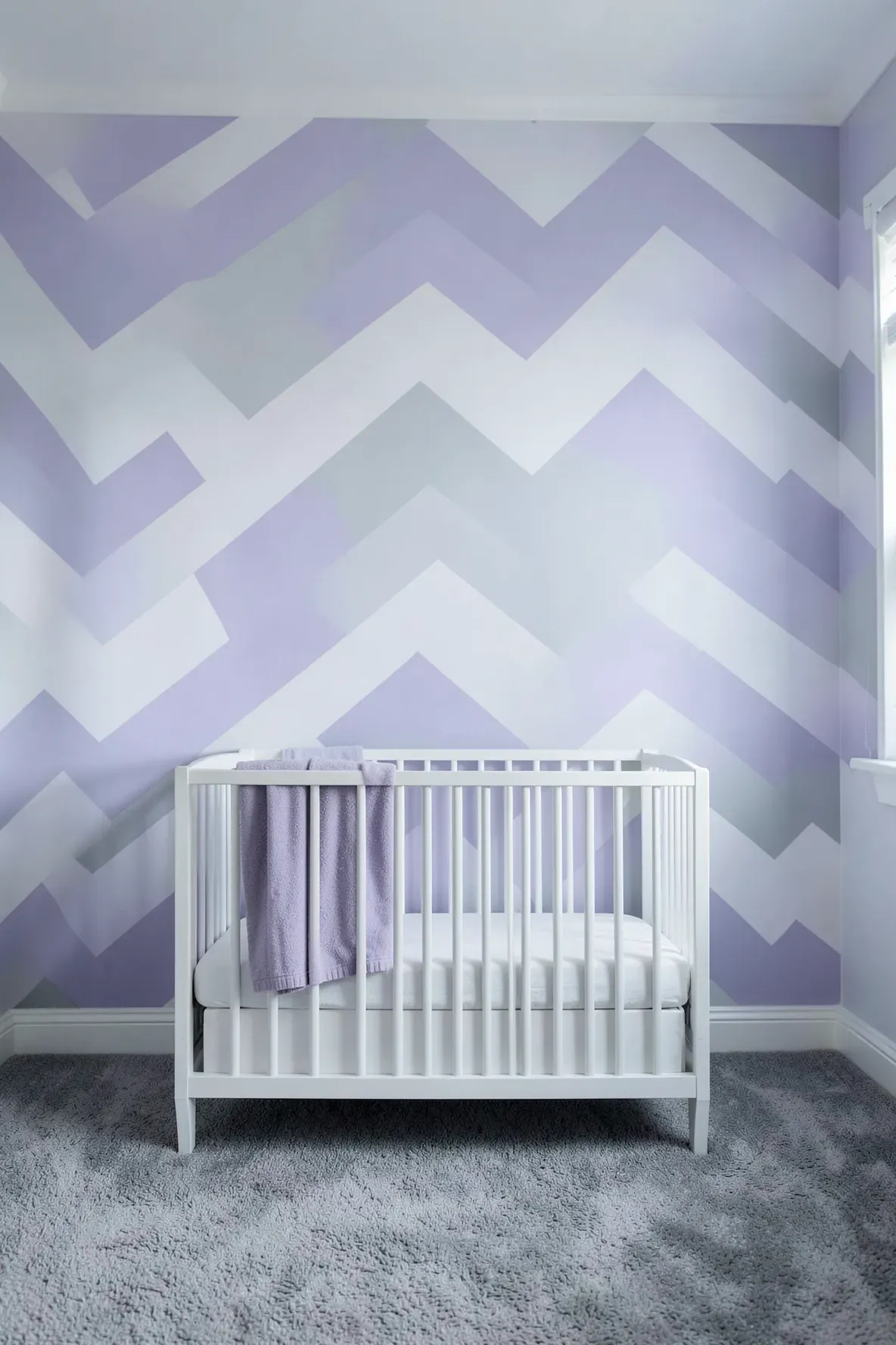 Oversized lavender and grey chevron stripes on a nursery accent wall behind a white crib.