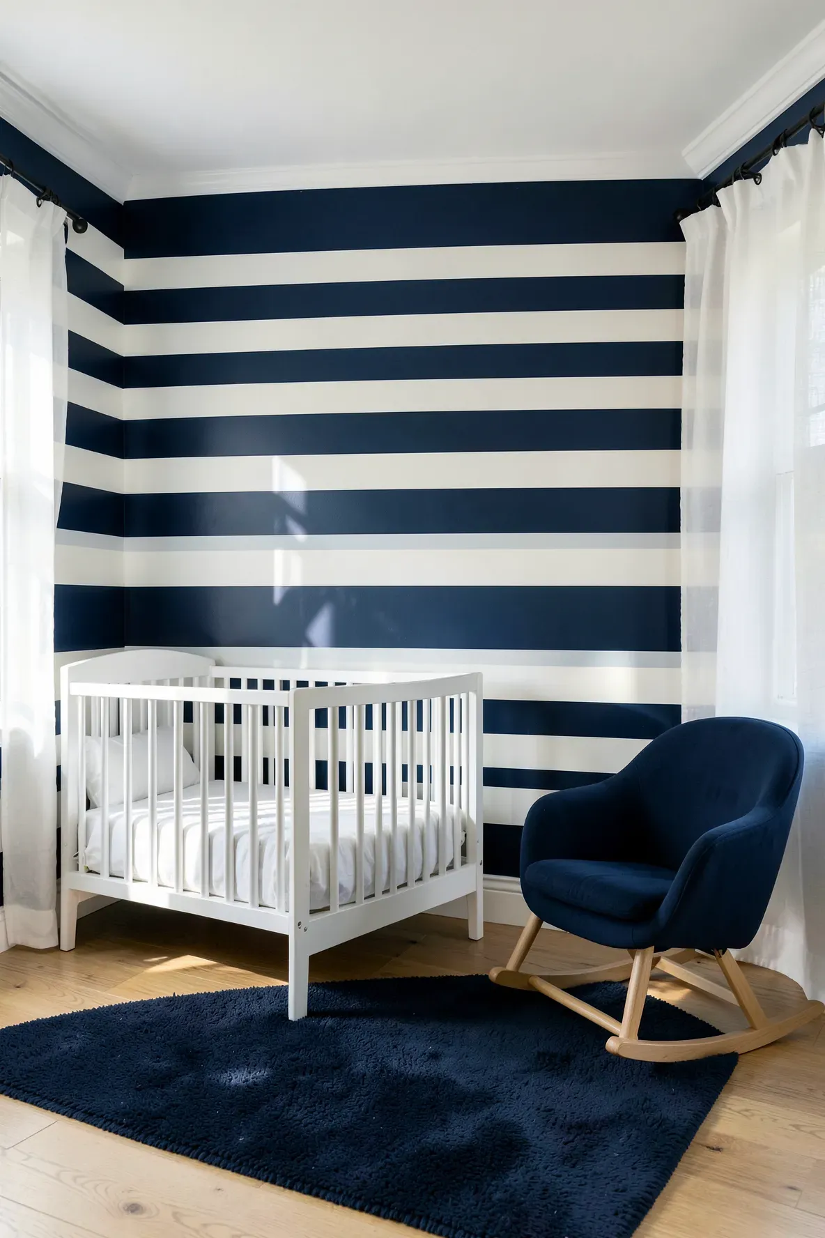 A modern nursery with a navy blue and white horizontal striped accent wall behind a white crib.