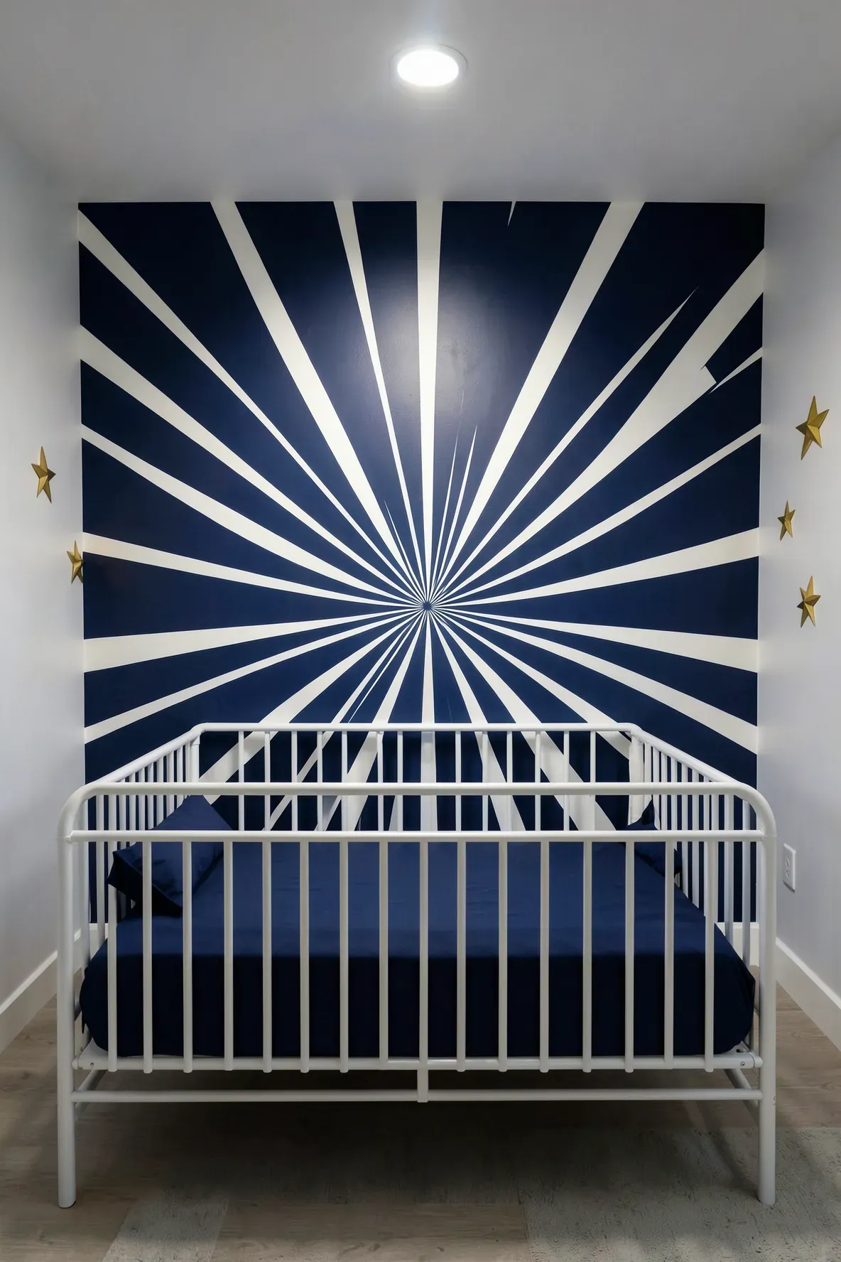 A bold navy and white starburst geometric pattern on a nursery wall behind a white crib.
