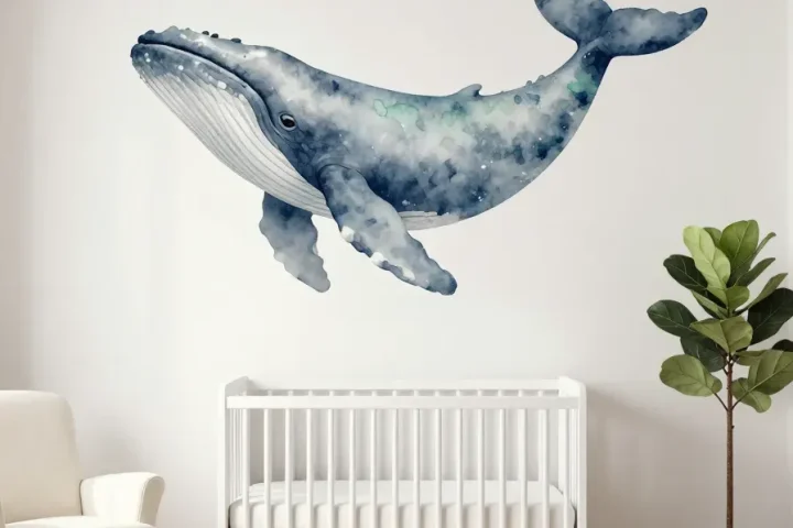 A serene nursery featuring a large watercolor whale mural behind a white crib with soft blue tones.
