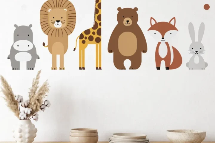 Minimalist nursery wall with a lineup of earth-toned animal decals like a hippo, lion, and bear above a wood cabinet.