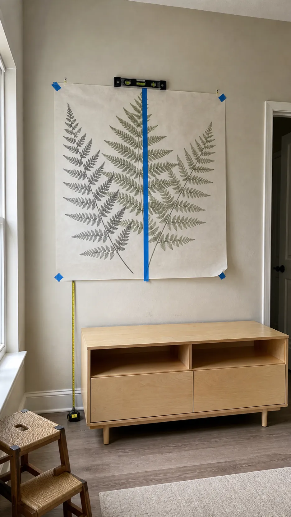 Large wall decal aligned with painter tape hinge before application