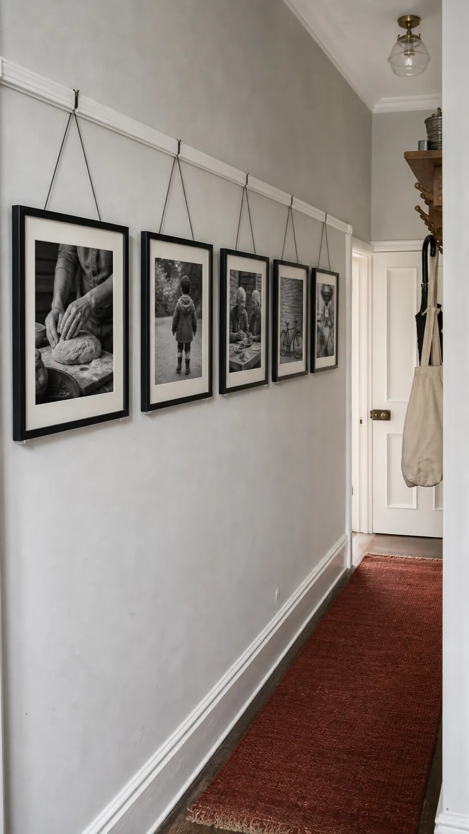 Narrow hallway with a calm line of family photographs hung from a picture rail