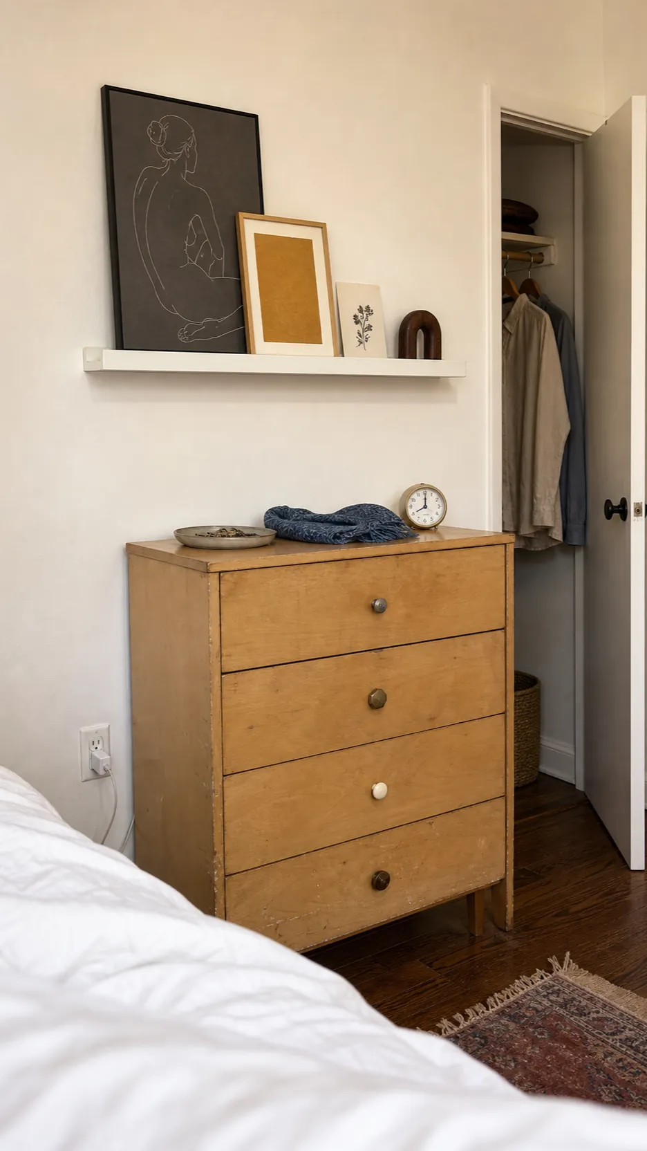 Renter friendly picture ledge on a bedroom side wall above a compact dresser
