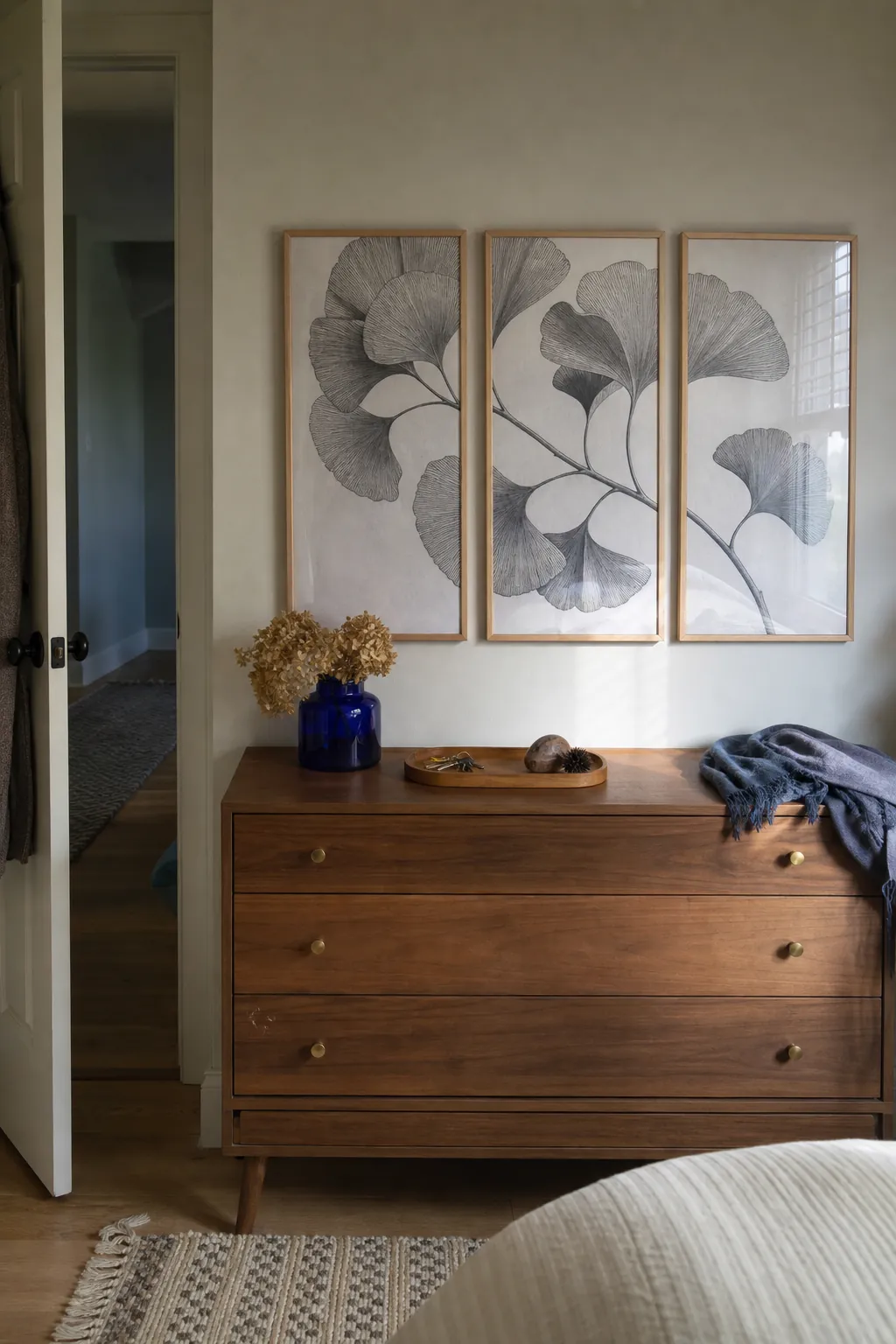 Three framed removable wallpaper panels above a rental bedroom dresser
