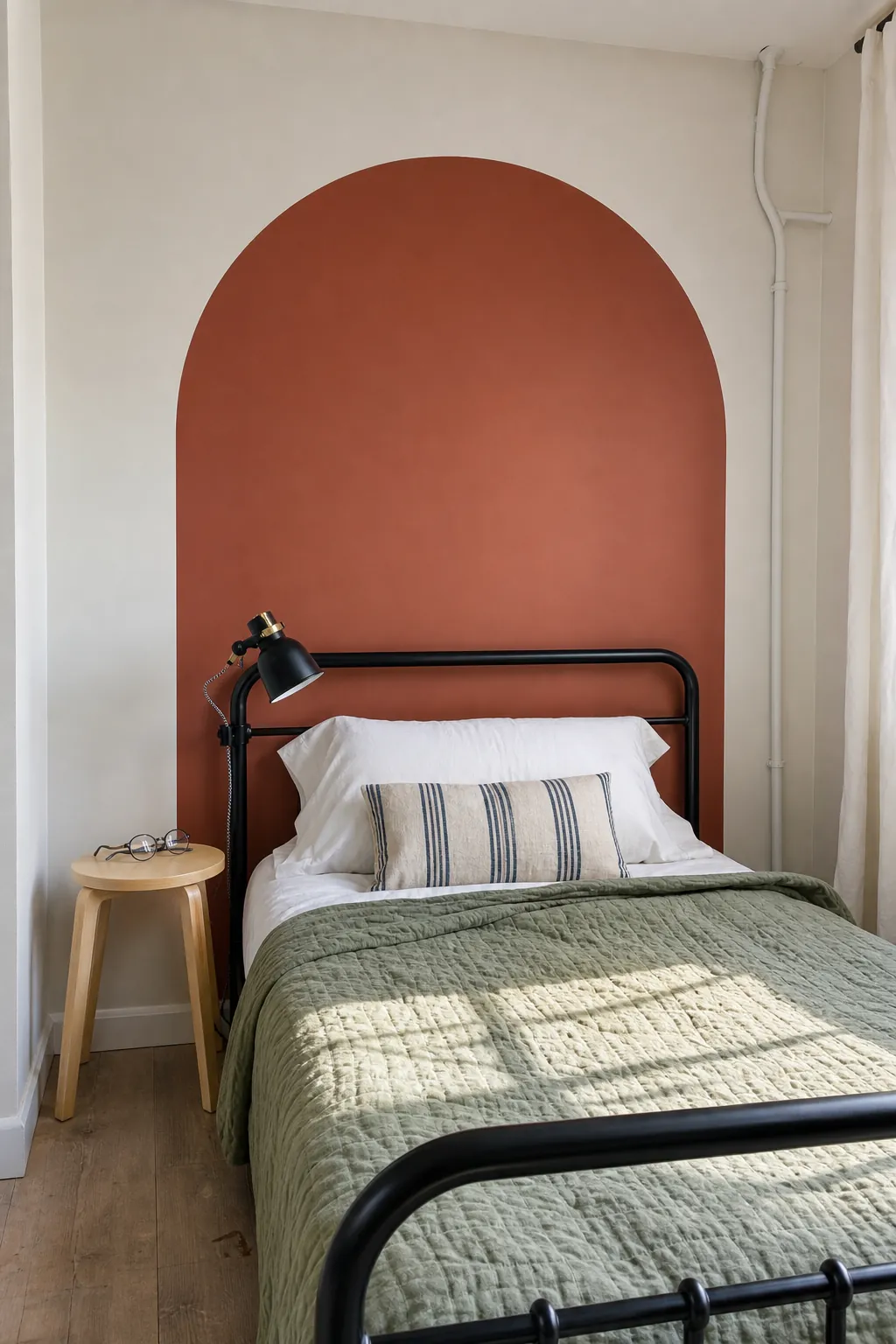 Terracotta peel and stick arch behind a bed in a small apartment bedroom