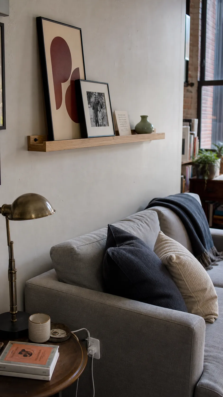 Shallow oak picture ledge with layered prints above a sofa