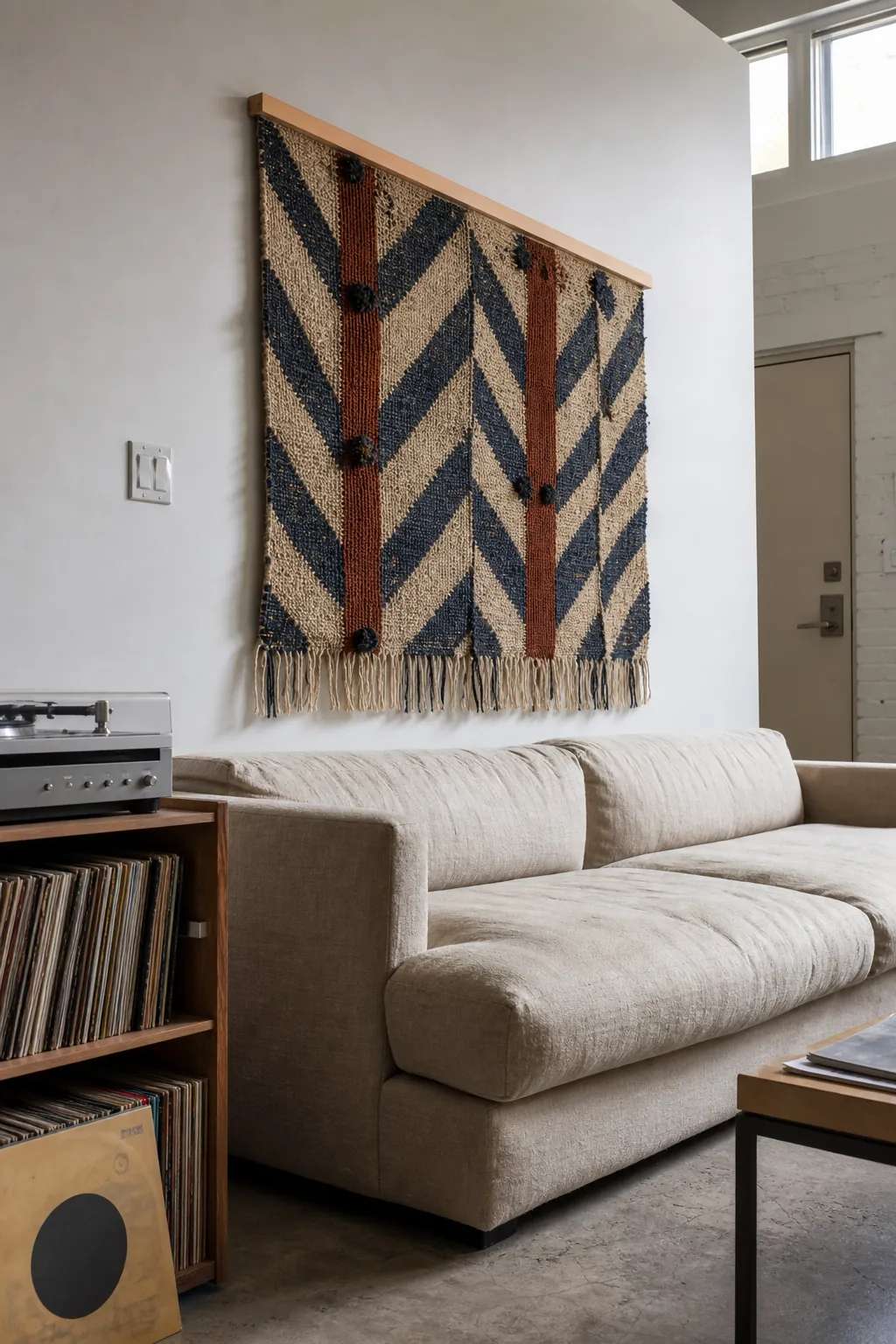 Wide geometric woven tapestry installed above a linen sofa