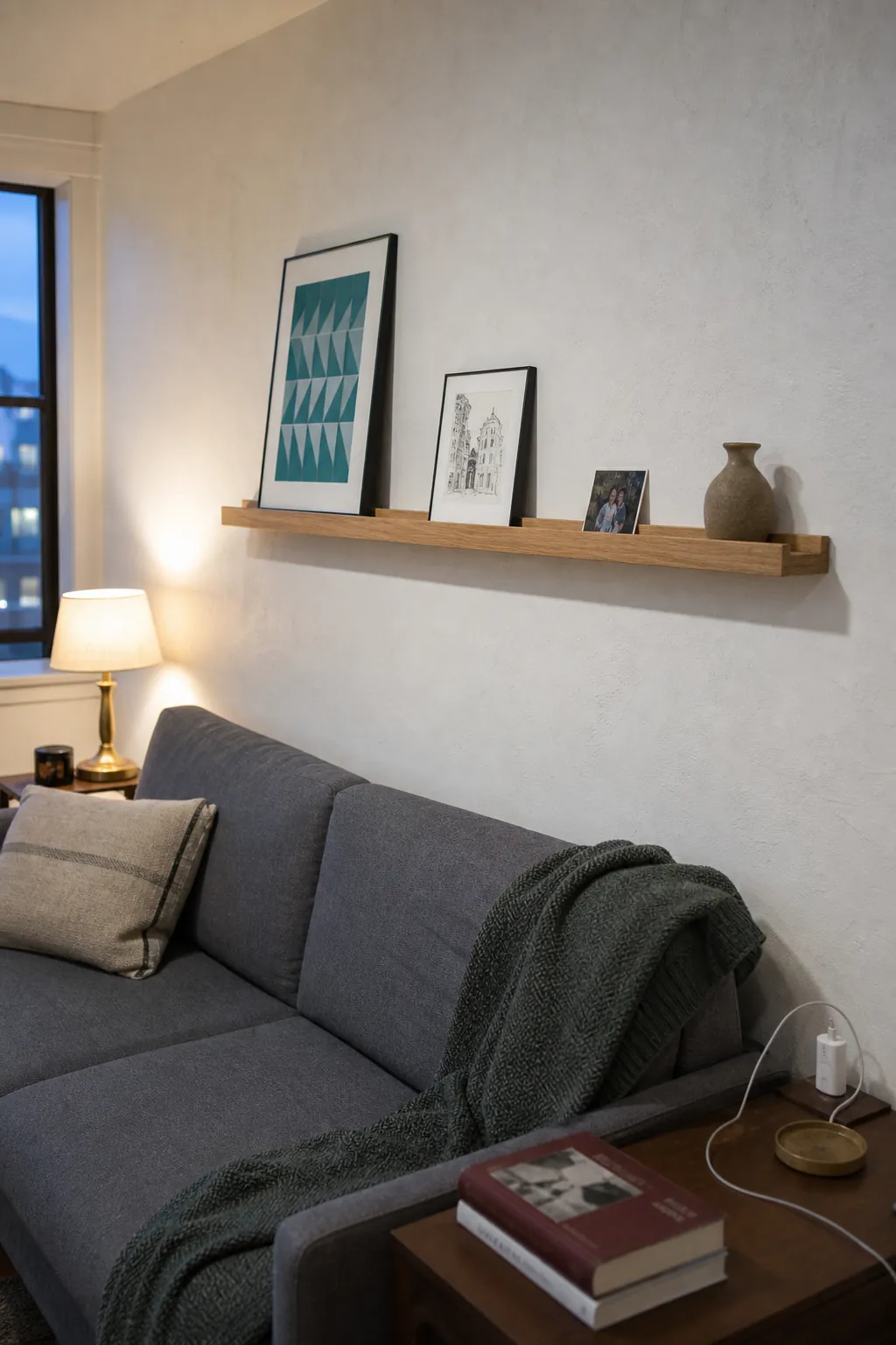 Shallow oak picture ledge with lightweight prints above a low sofa