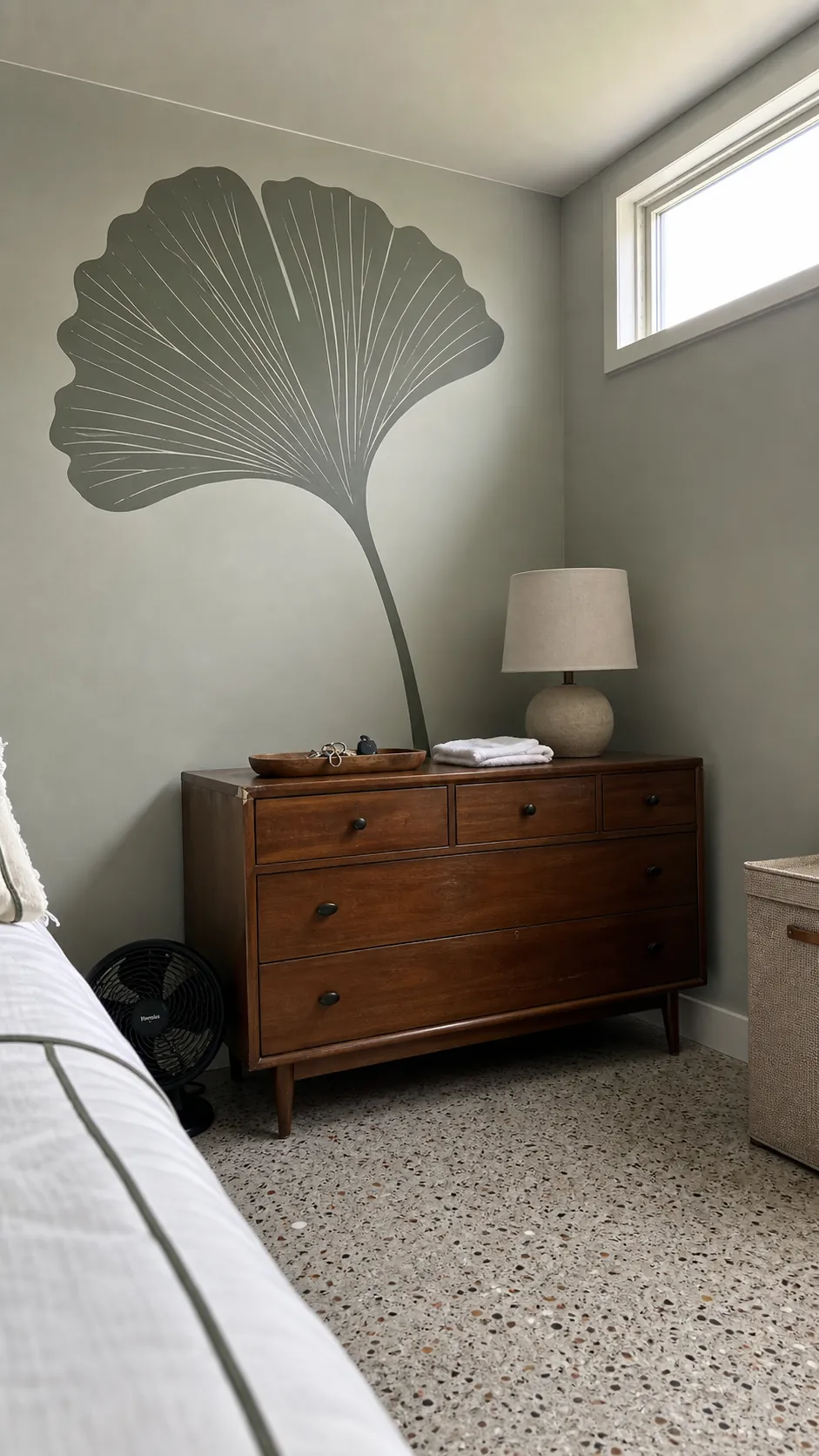 Oversized muted ginkgo leaf wall decal behind a bedroom dresser