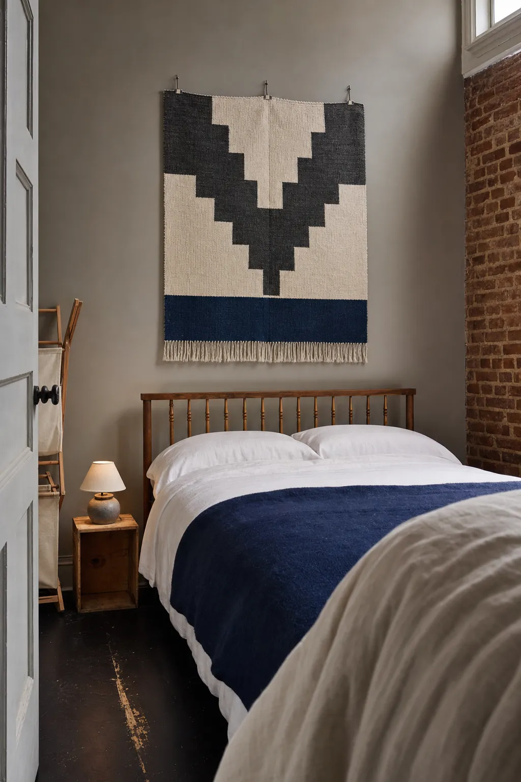 Large flat woven textile hanging above a bed in a compact bedroom