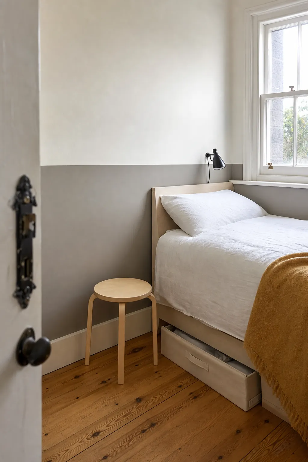 Low-contrast half-wall decal grounding a bed in a tiny bedroom