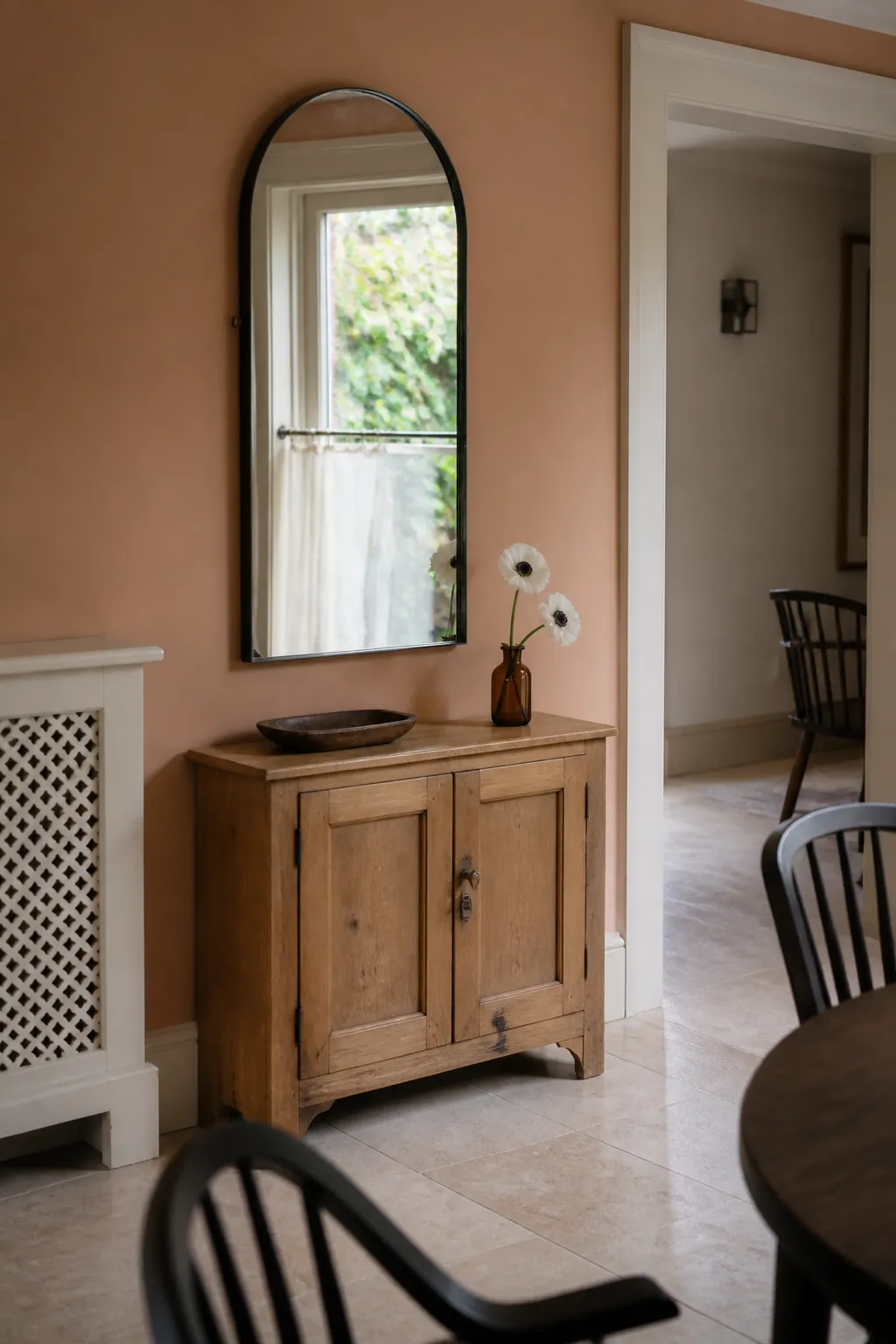 Arched mirror borrowing window light as decor for a short wall