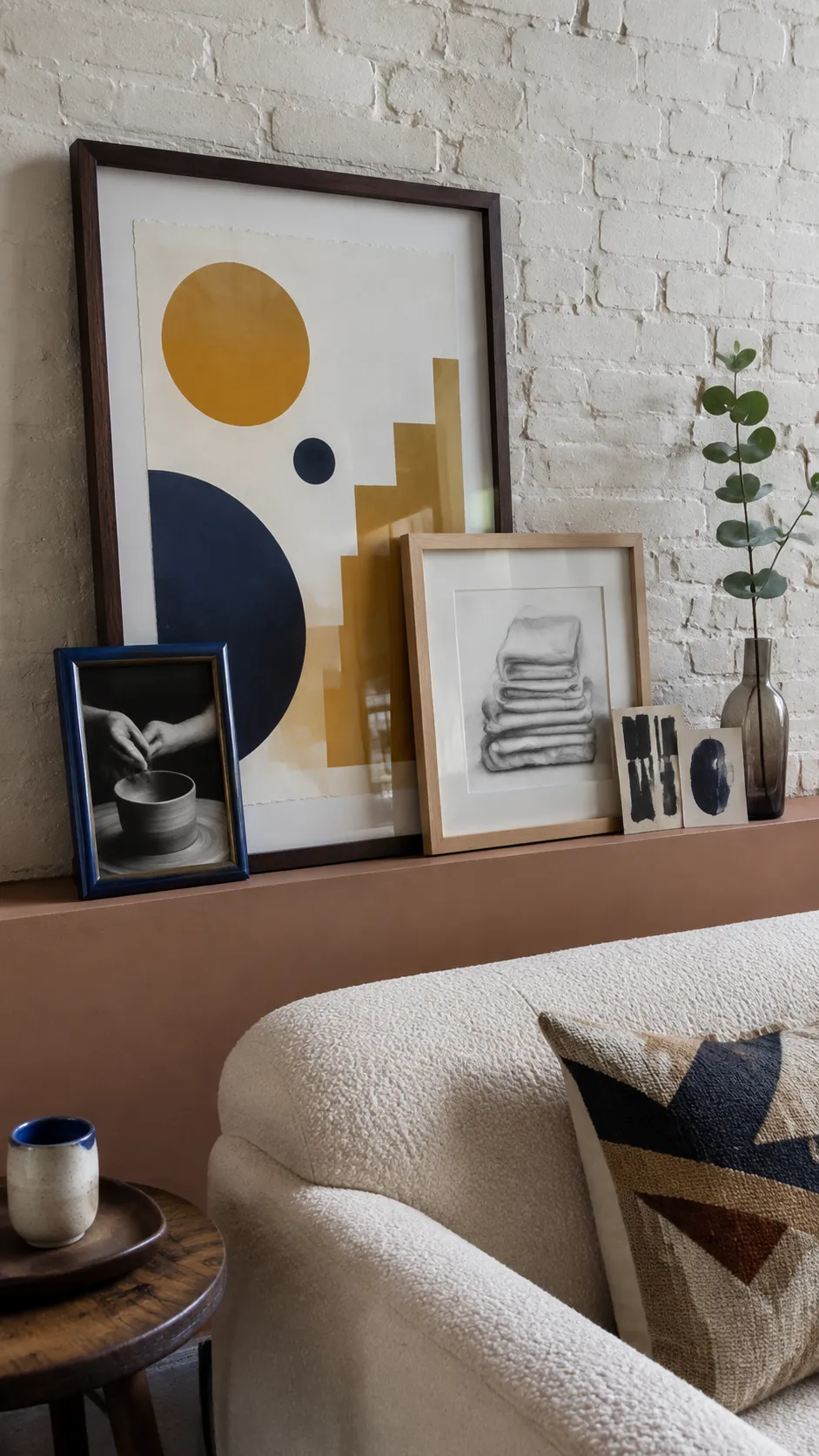 Layered frames on an art ledge with one dominant anchor piece