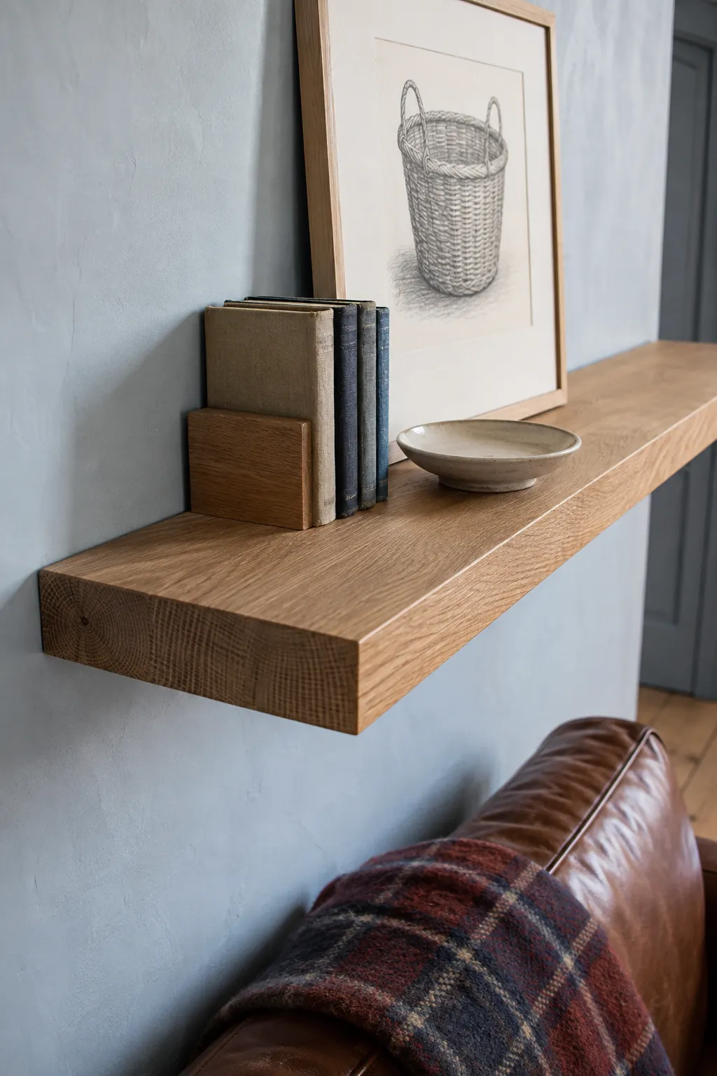 Securely mounted oak floating shelf with light decor above a sofa