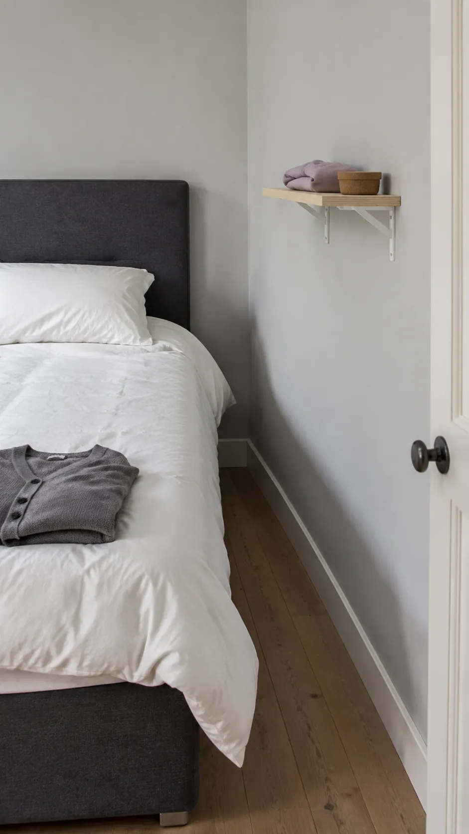 Shallow bracketed shelf on a side wall beside a bed