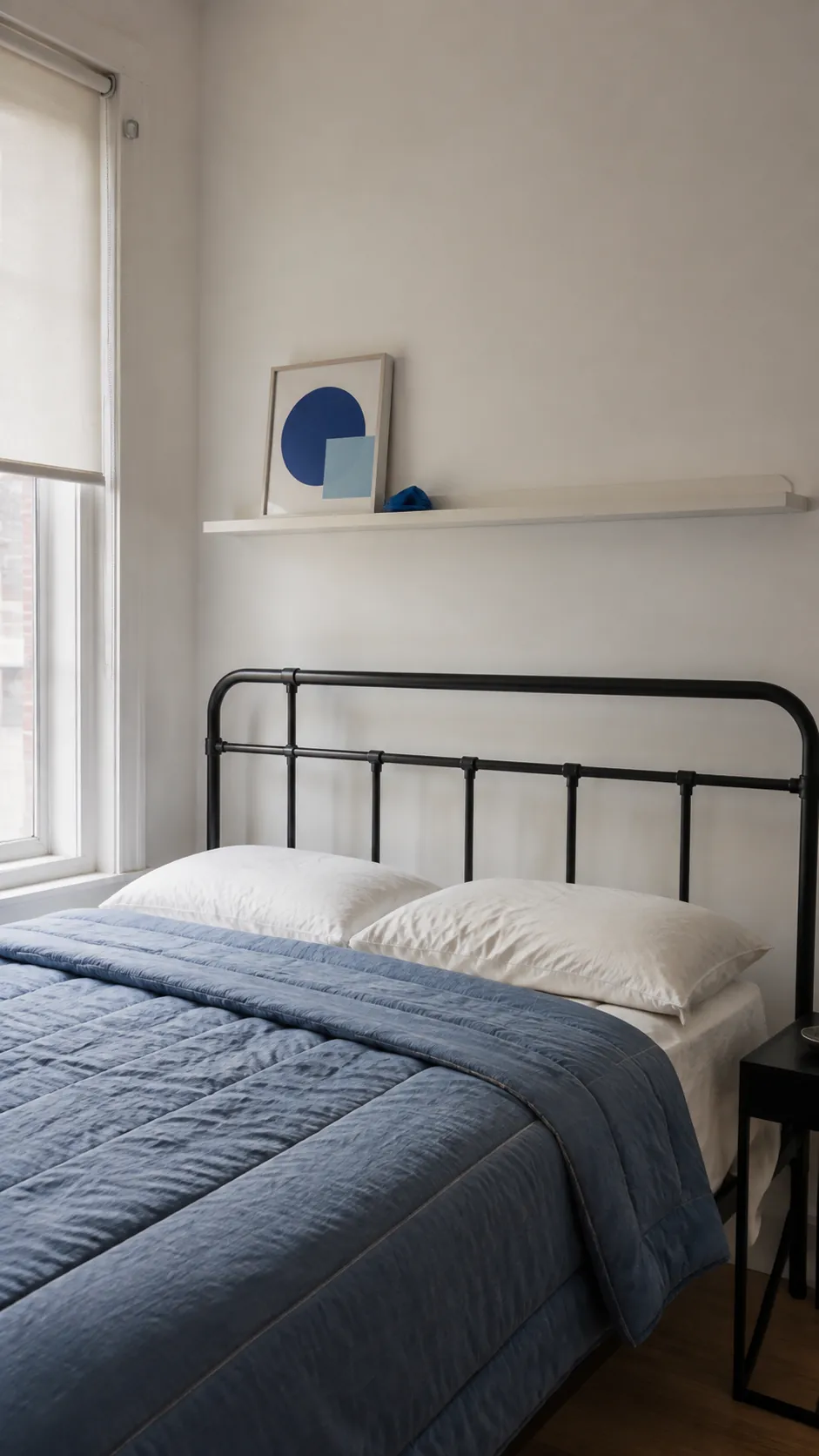 Sparse blue abstract print arrangement above a dark metal bed