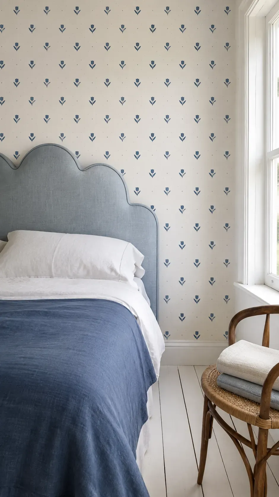 Indigo stamped floral wallpaper behind a scalloped headboard
