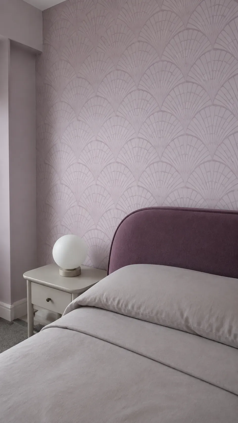 Tonal Art Deco fan wallpaper beside a rounded upholstered bed