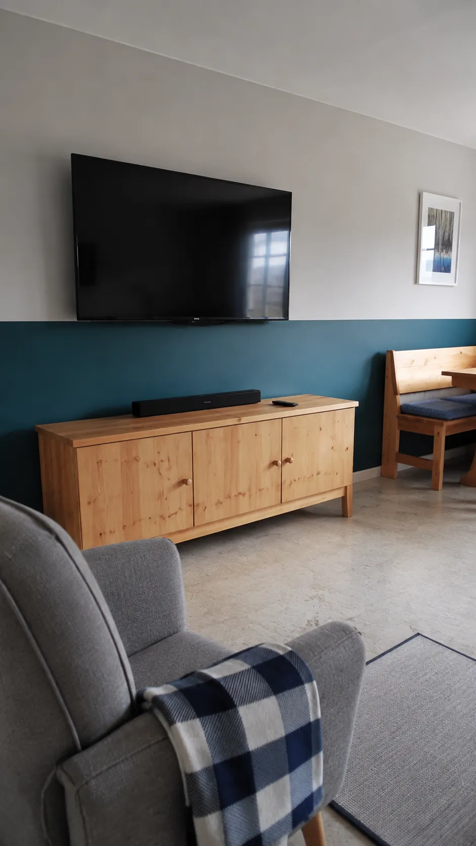 A low two tone wall behind a television in a lived in room