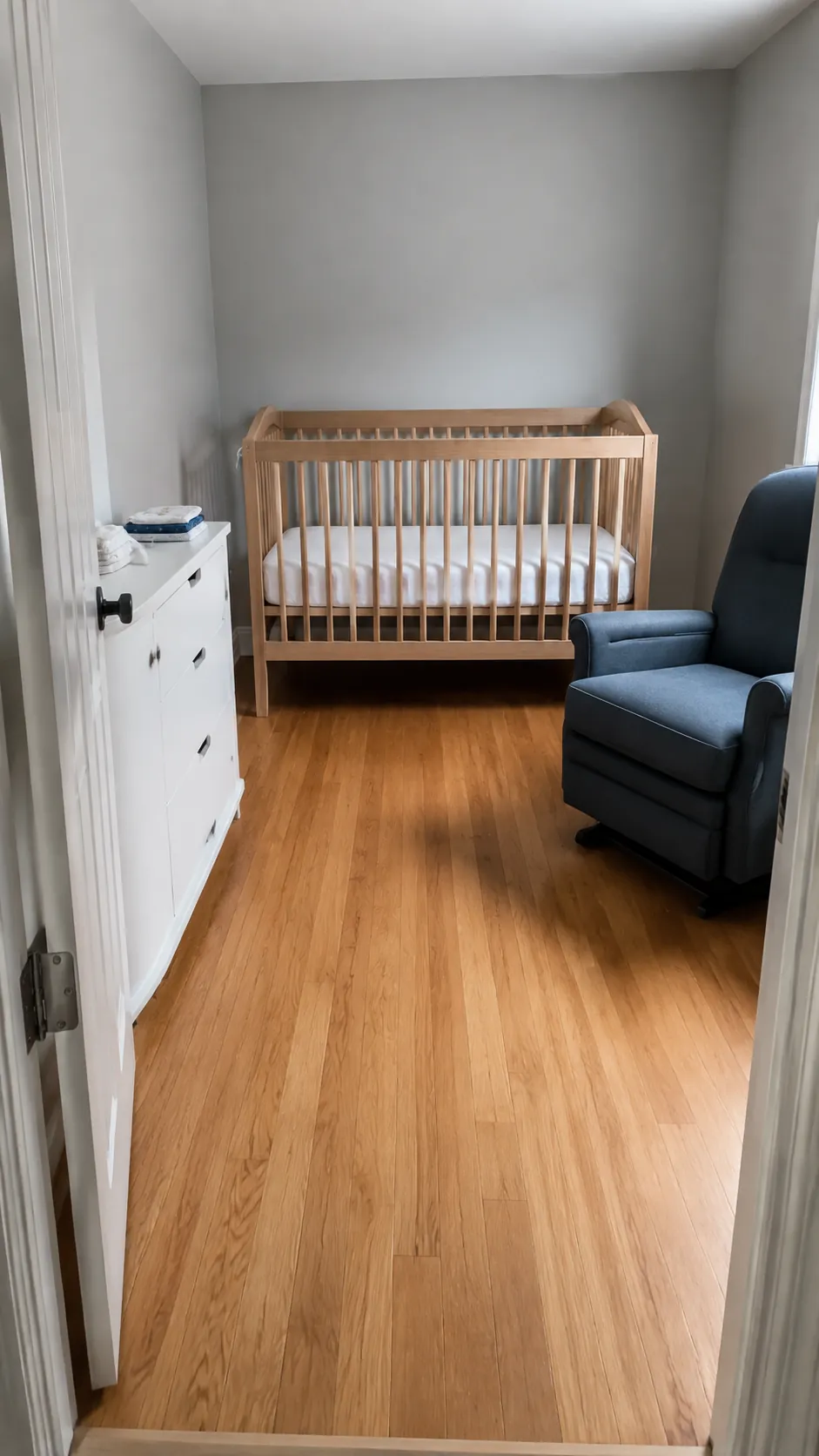 Show how three substantial nursery furniture pieces can occupy three separate walls while leaving an honest, usable center in a compact square spare bedroom