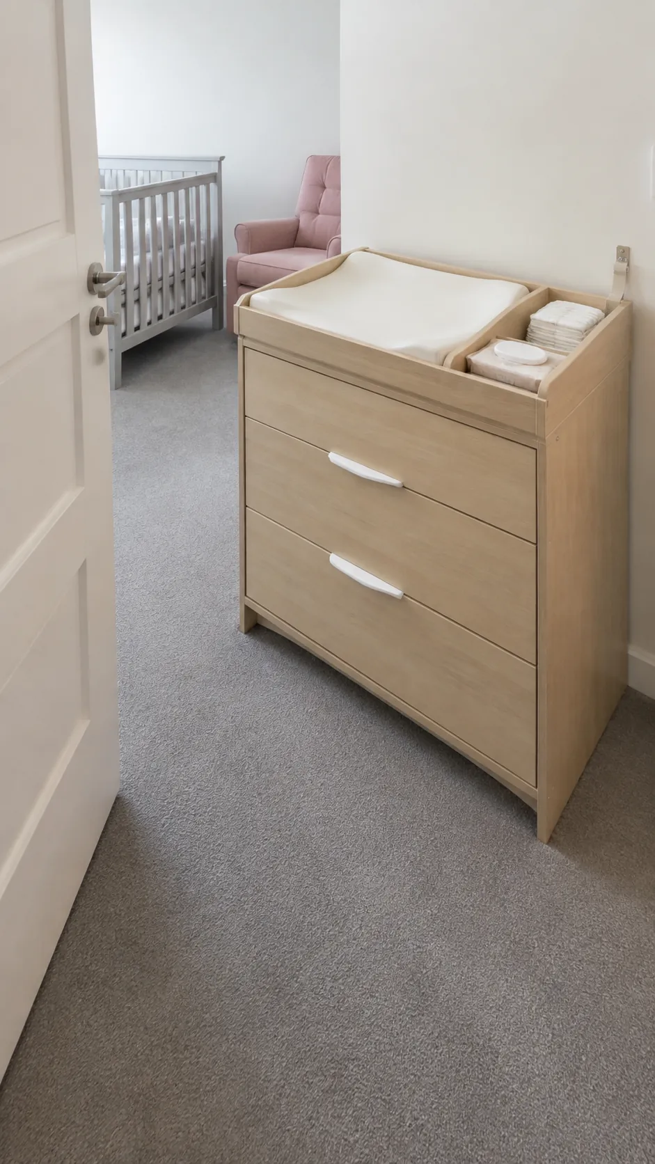 Illustrate a changing and storage station placed immediately beside the nursery entrance, so the room can be entered without crossing to the far wall for basic supplies