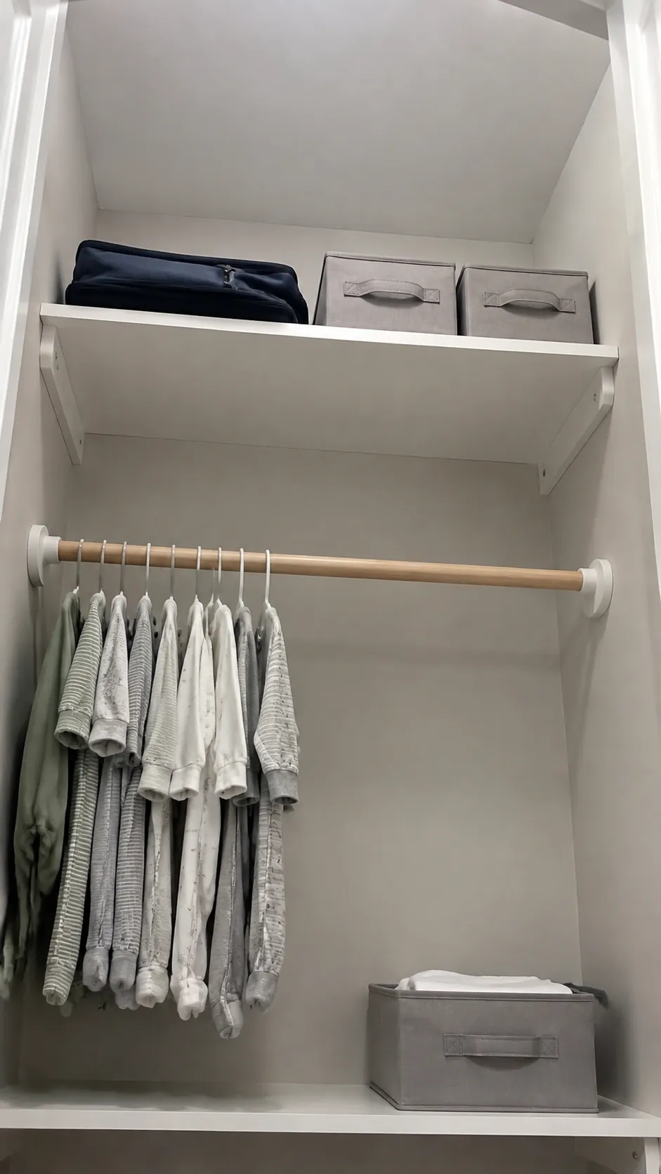 Photograph an upper nursery closet shelf used only for light occasional items, with heavier daily storage visibly lower