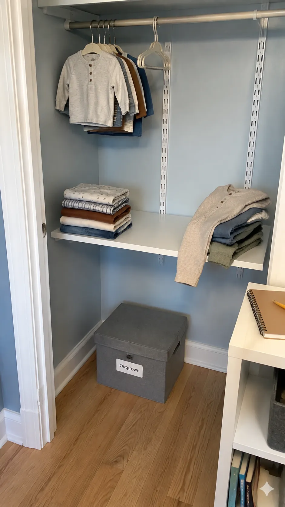Photograph a nursery closet during a small clothing rotation review, with current garments, an outgoing box, and a few incoming pieces clearly separated