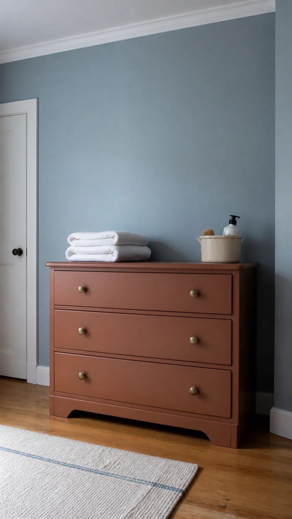 Dusty Blue and Burnt Clay nursery with burnt clay painted dresser against dusty blue walls