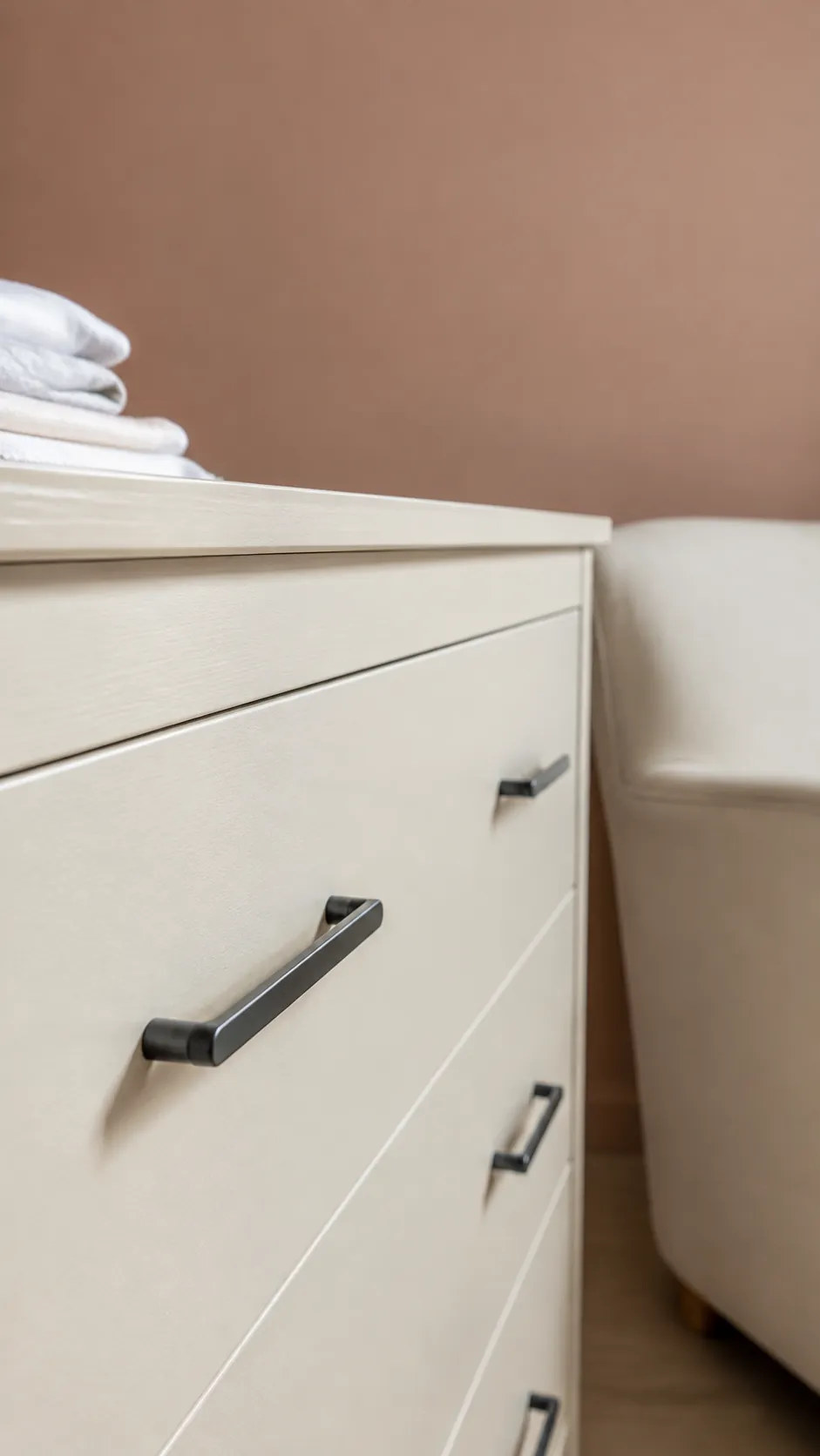 Charcoal and Pale Terracotta nursery with cream dresser with charcoal handles beneath a pale clay wall