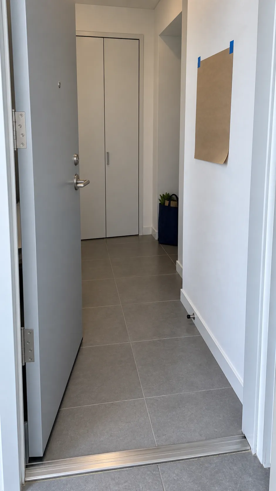 Photograph the everyday geometry of a narrow apartment entrance so a reader can understand why the walking passage must be considered before projecting objects are installed