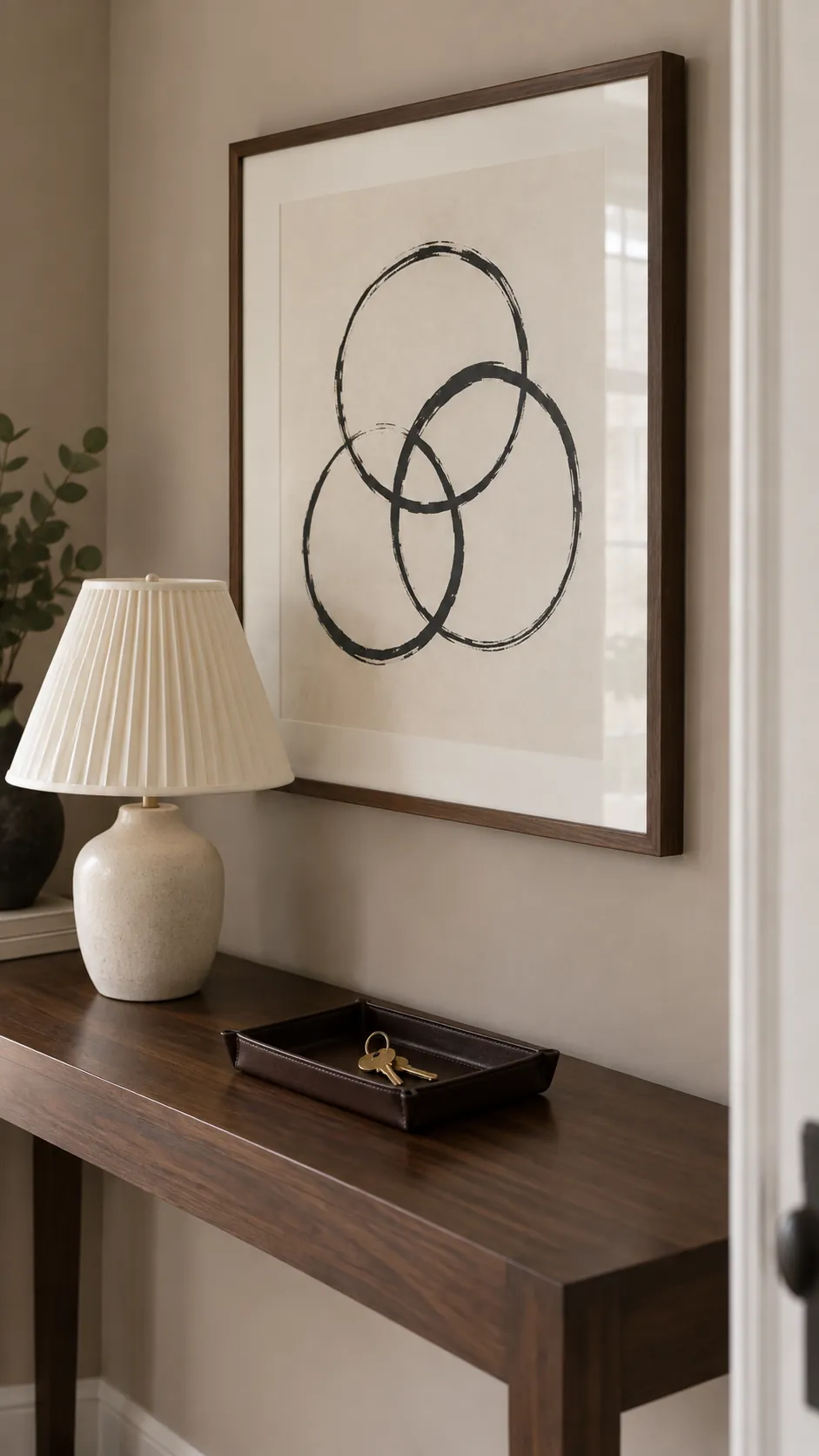 Make an intimate photograph of the height relationship between a framed print and a console lamp, showing a small amount of visual layering without covering the artwork subject