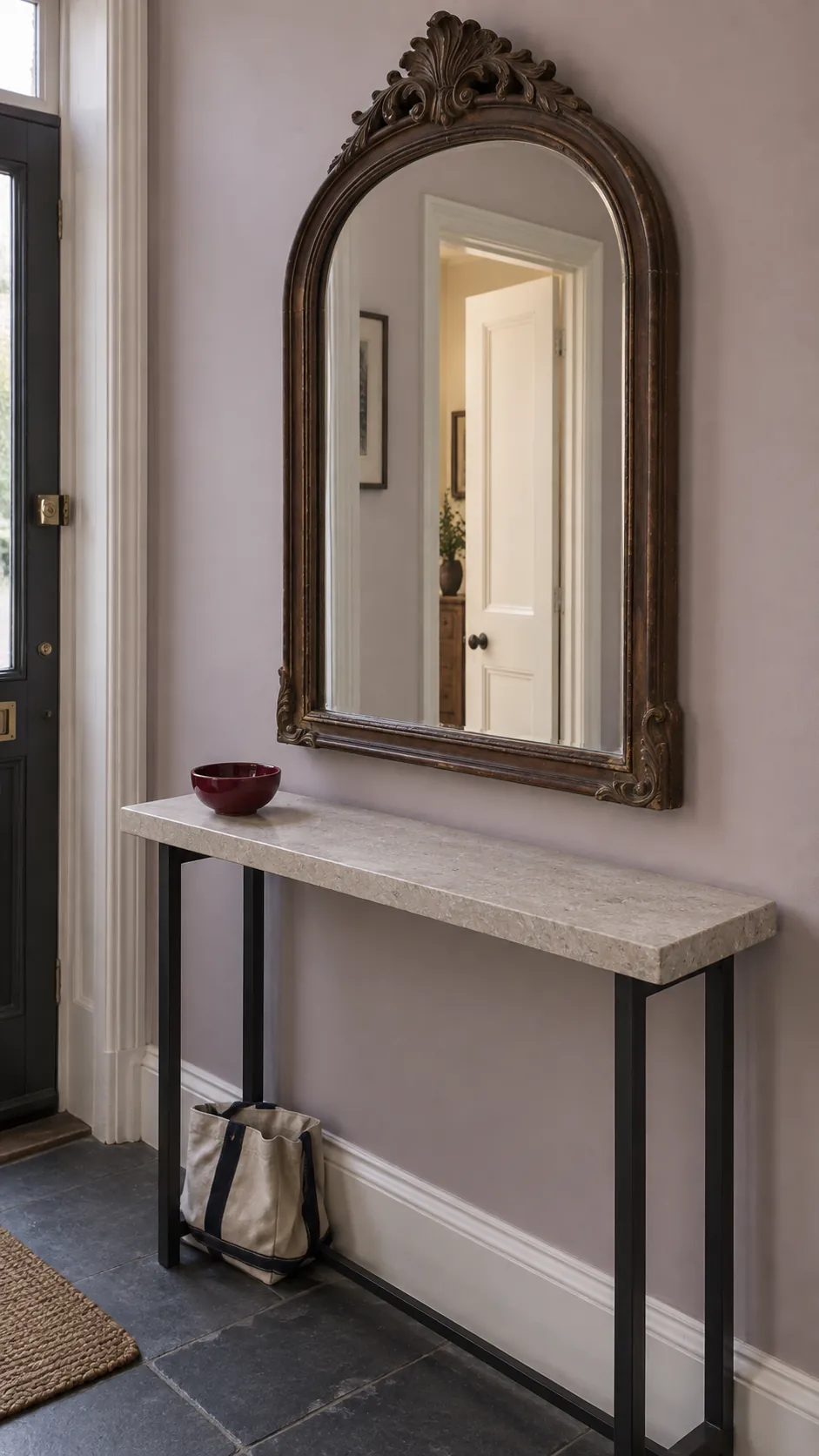 Carved arched mirror paired with a simple pale stone console